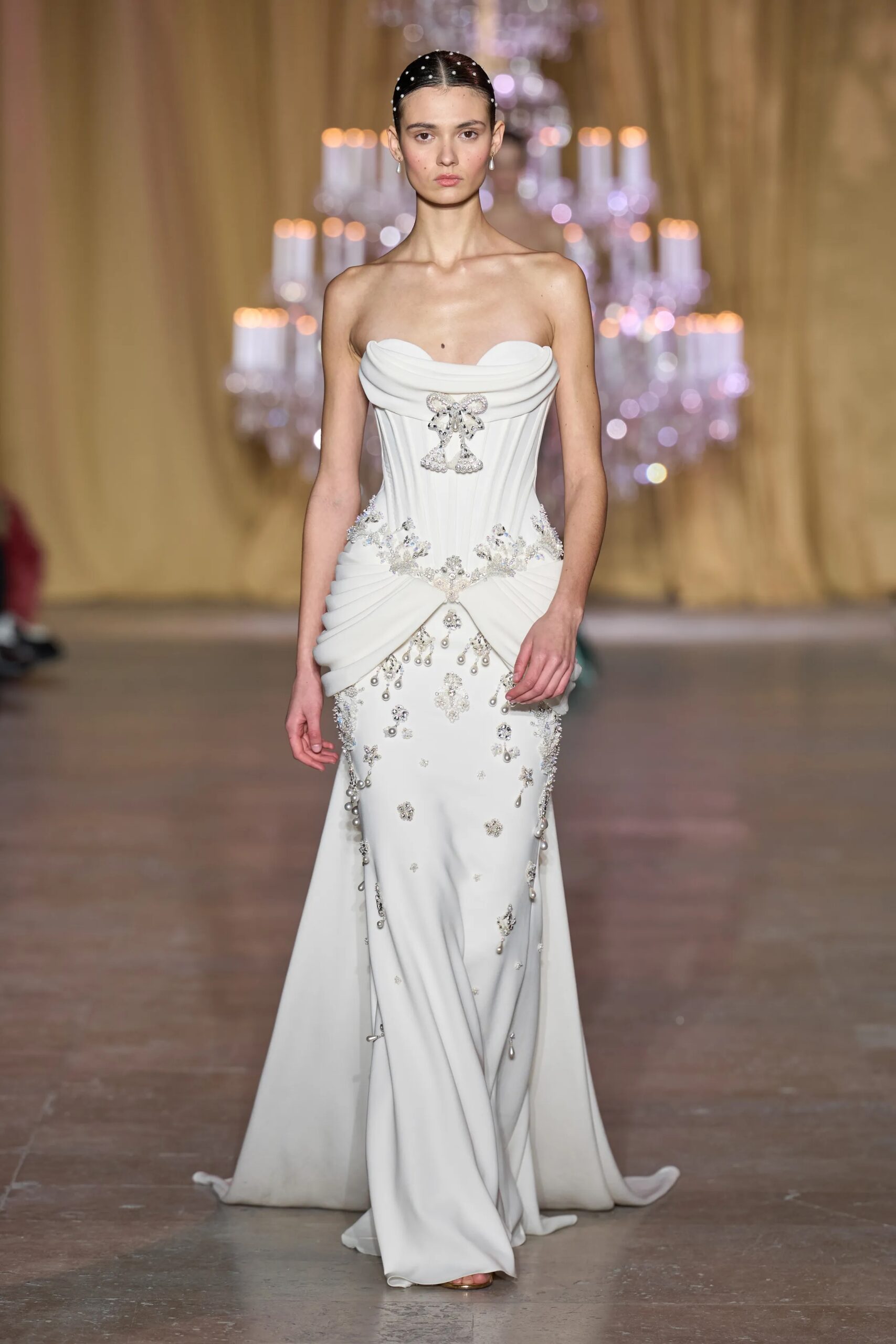 Model walking in Zuhair Murad Spring 2026 Couture wearing an ivory embroidered corset gown with crystal embellishment and draped detailing