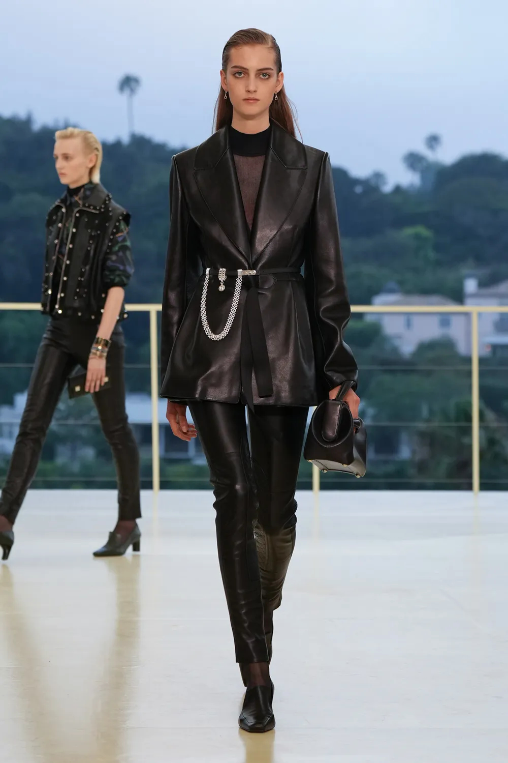 Model wearing a black leather blazer with silver chain embellishments, leather trousers, and black ankle boots at the Hermès Fall-Winter 2026 runway show.