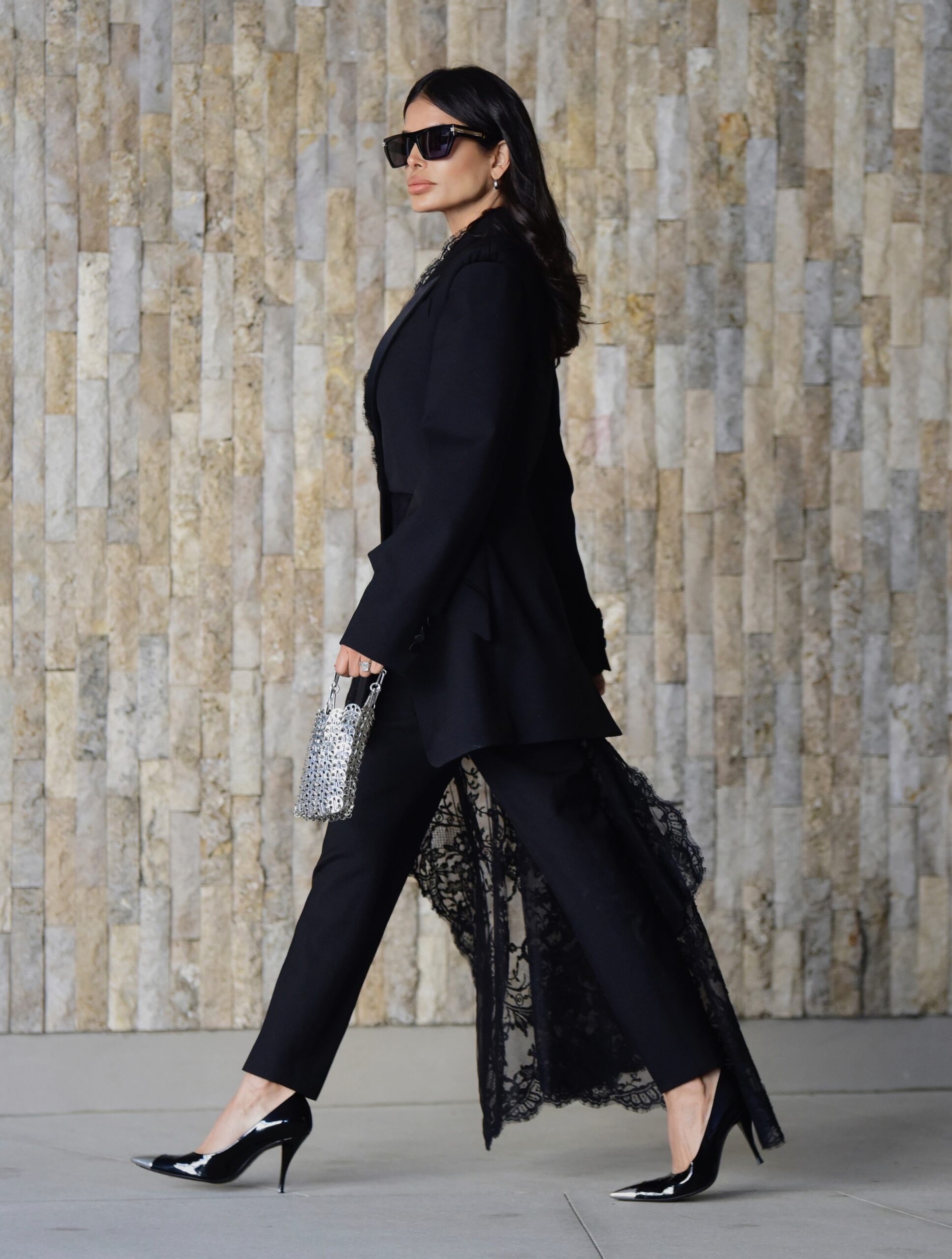 Victoria Barbara wearing an Alexander McQueen black tailored blazer and trousers with lace detailing, Givenchy sunglasses, Paco Rabanne bag, and Saint Laurent heels in Los Angeles.