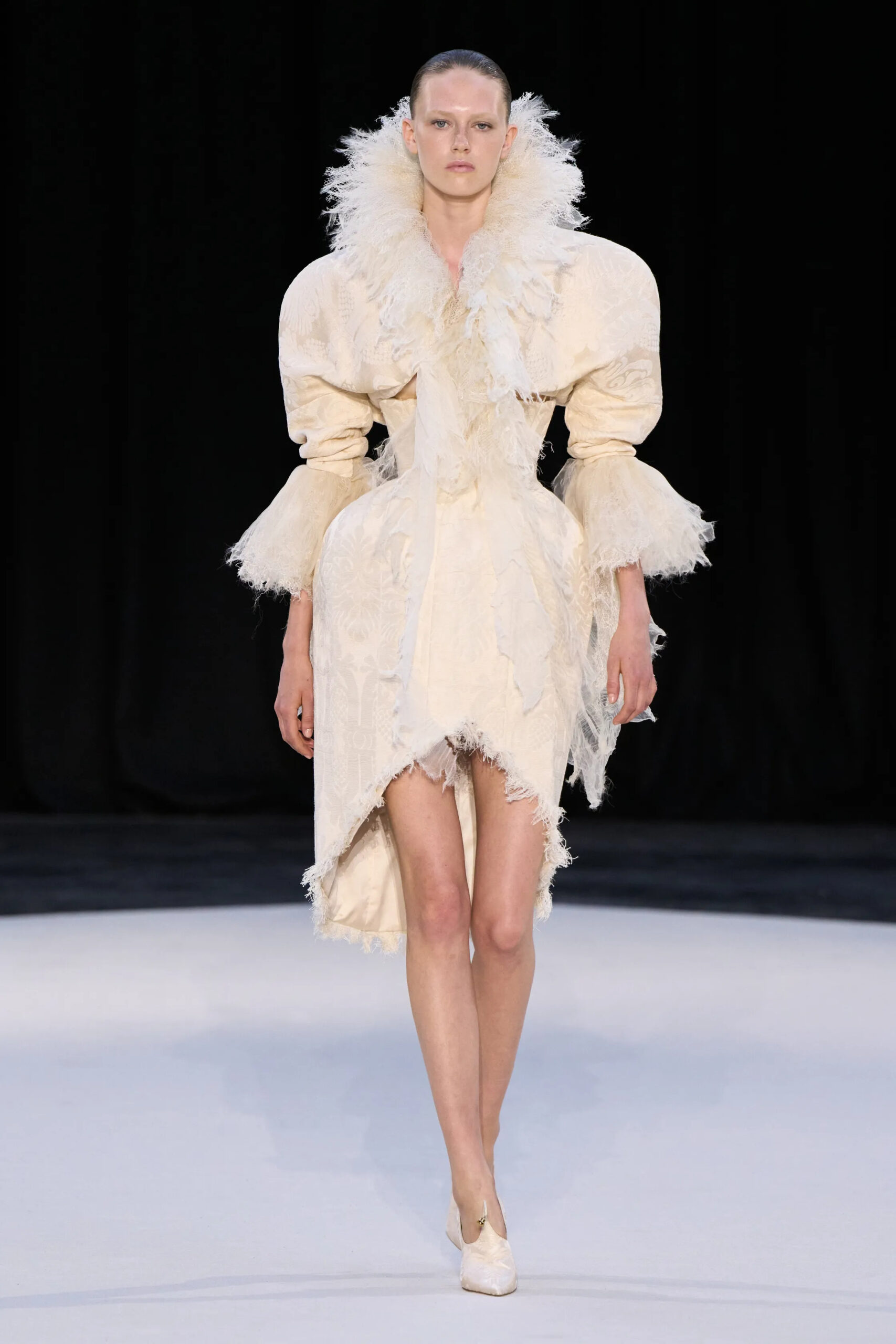Model wearing an ivory feathered couture dress with dramatic shoulders and sculpted proportions at Ashi Studio Fall 2026 Couture
