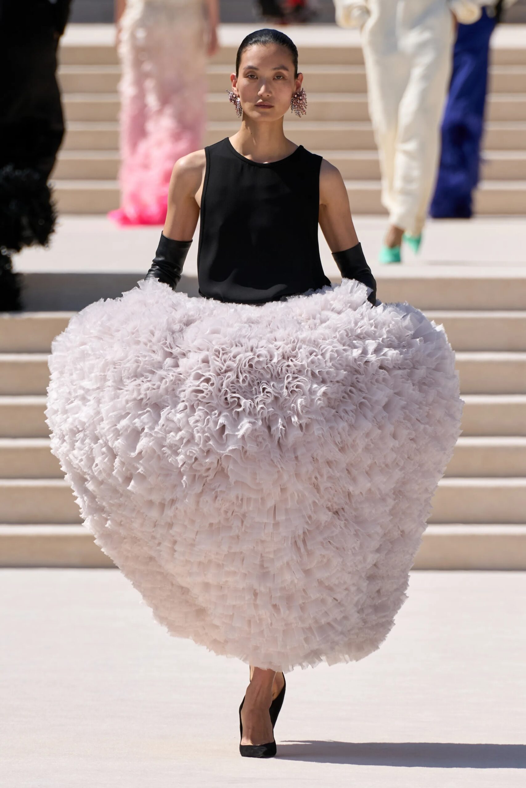 Model wearing a black sleeveless top with an oversized sculptural white couture skirt by Balenciaga