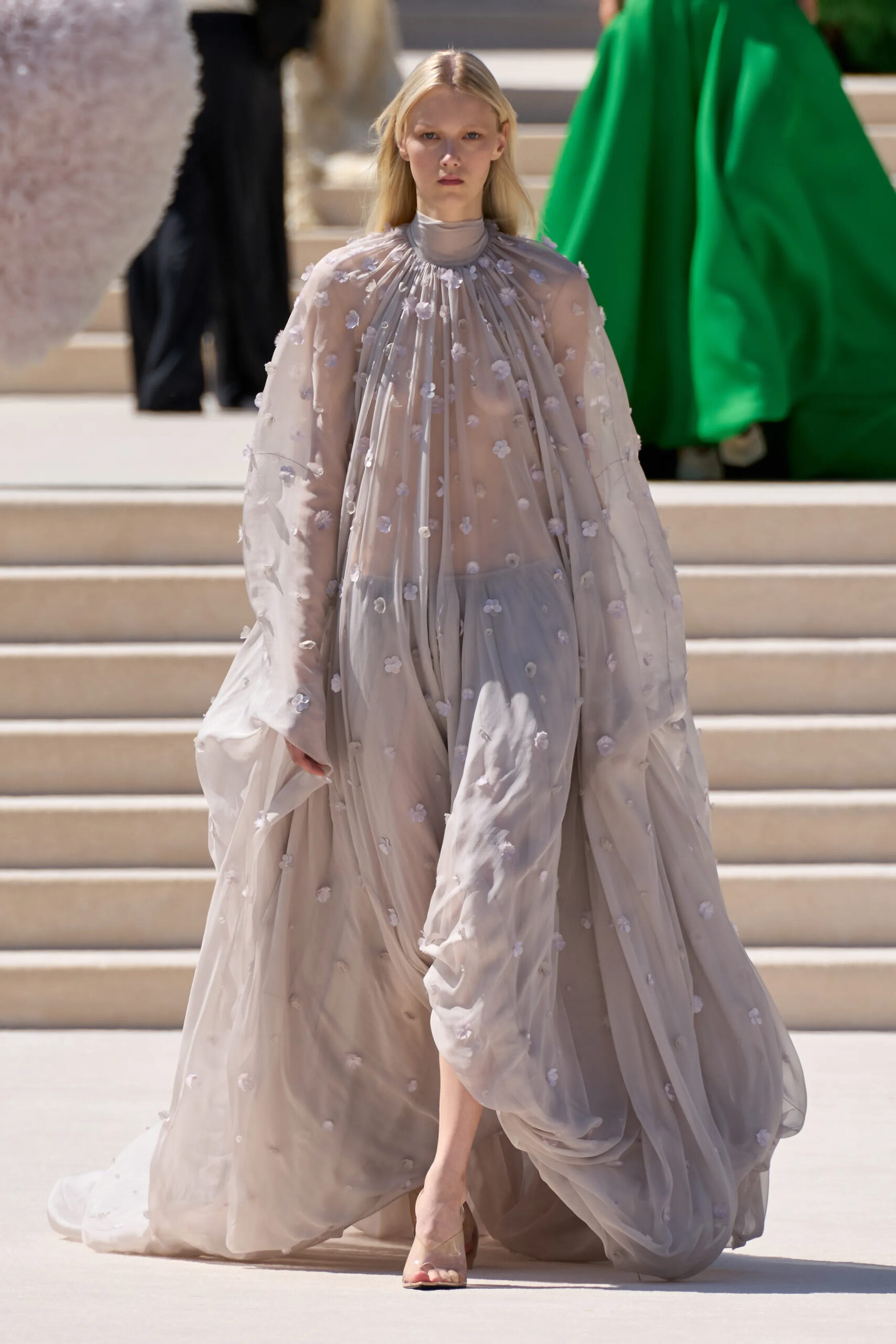 Model wearing a sheer draped couture gown with delicate floral embellishments by Balenciaga