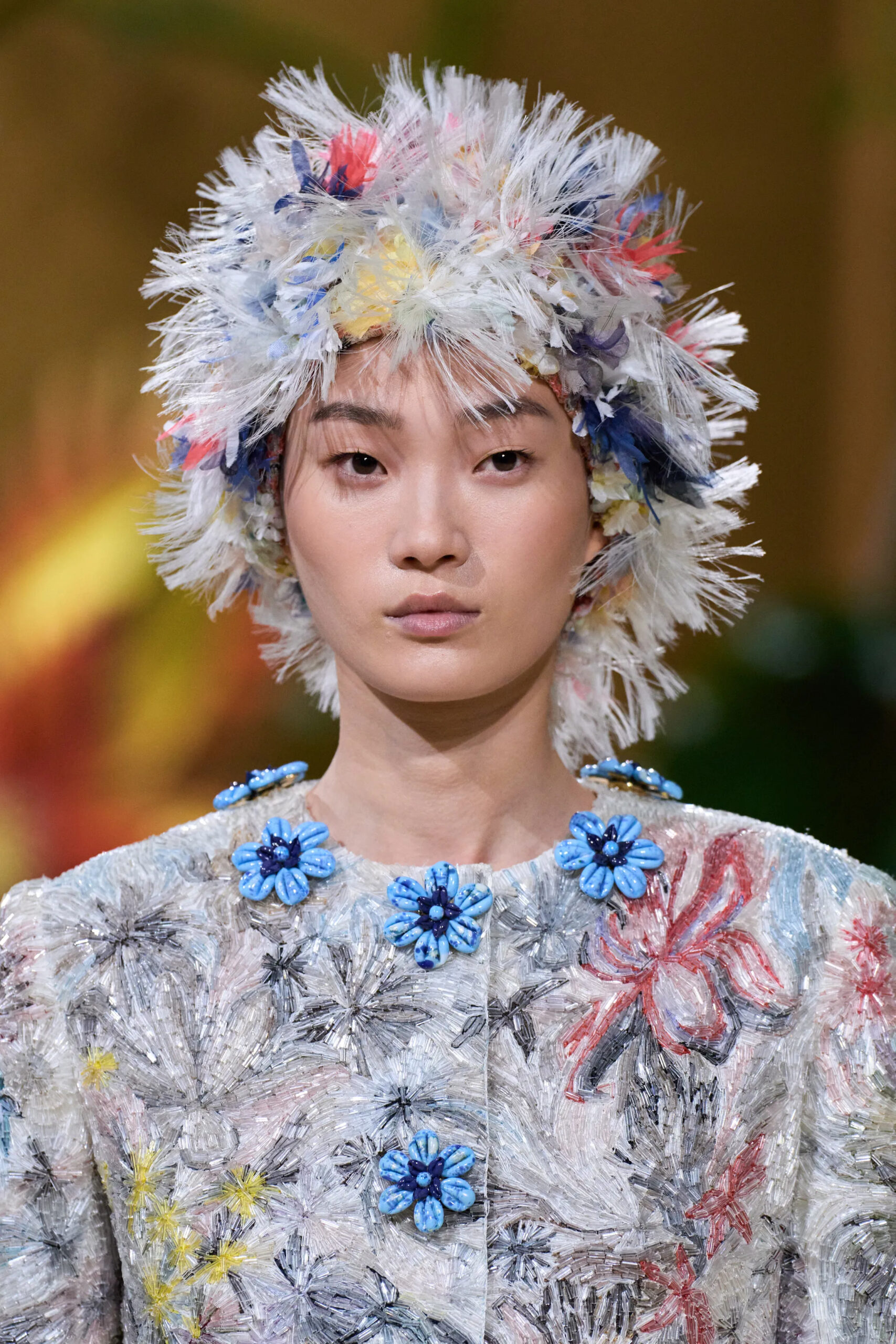 Model wearing a sculptural multicolored floral headpiece from the Chanel Fall 2026 Couture collection by Matthieu Blazy