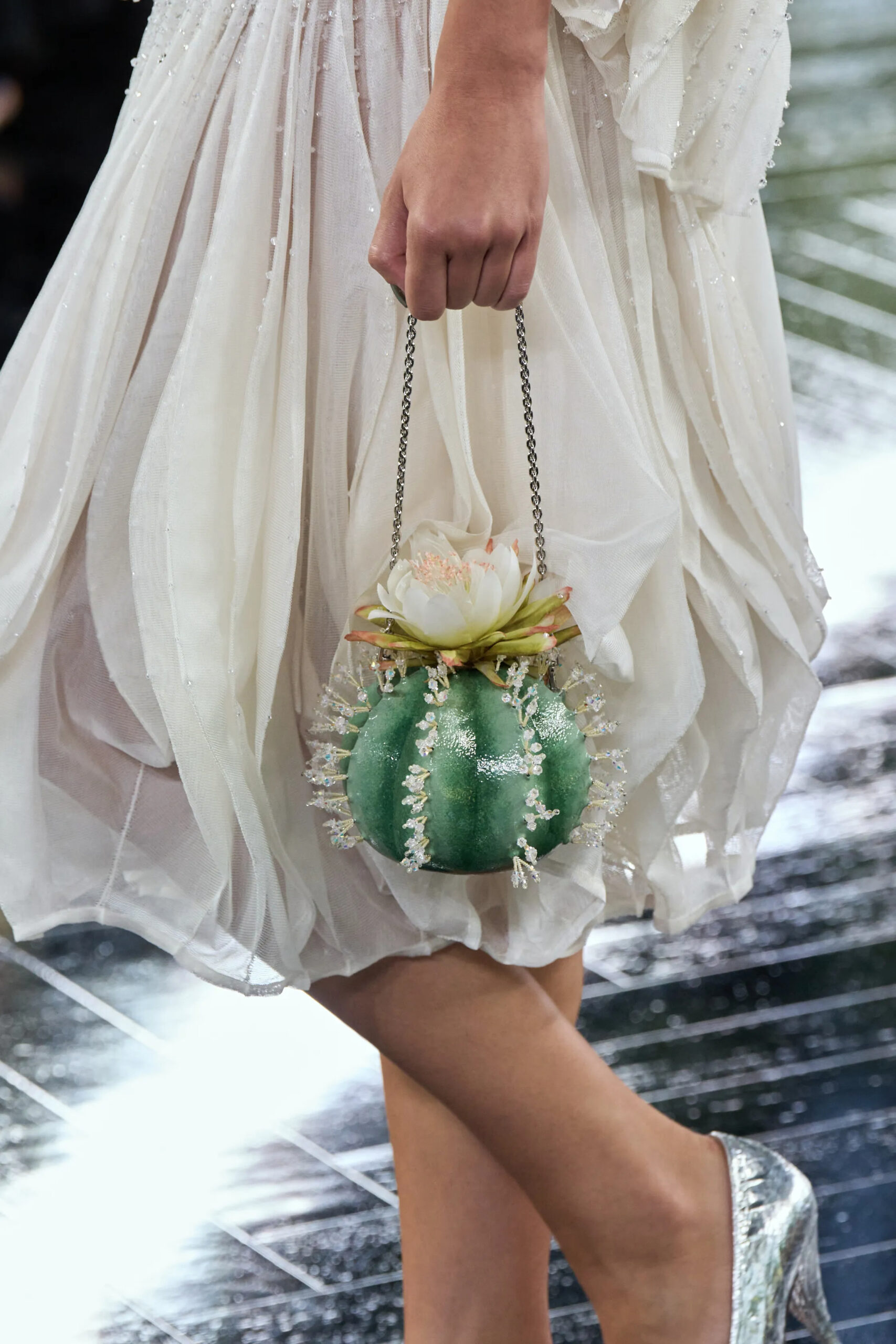 Green lotus-inspired Chanel minaudière carried with an ivory look from the Fall 2026 Couture collection