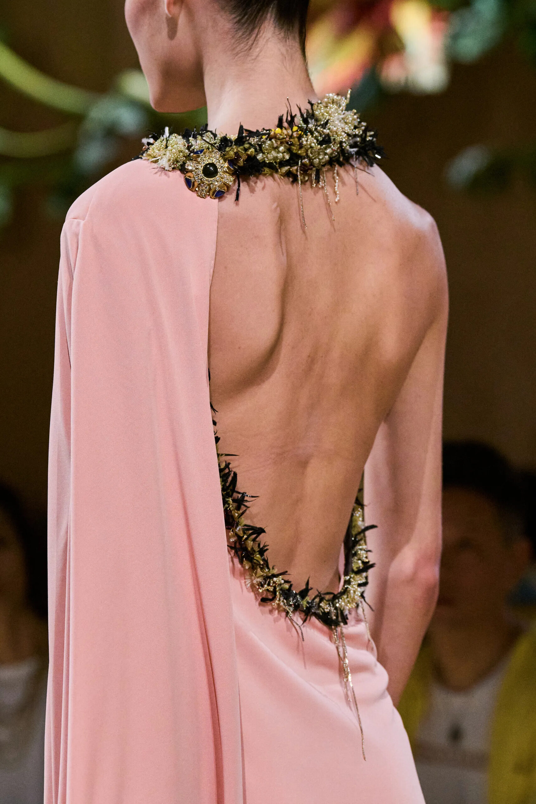 Rear view of a blush Chanel couture gown featuring an open back framed by embroidered floral embellishments