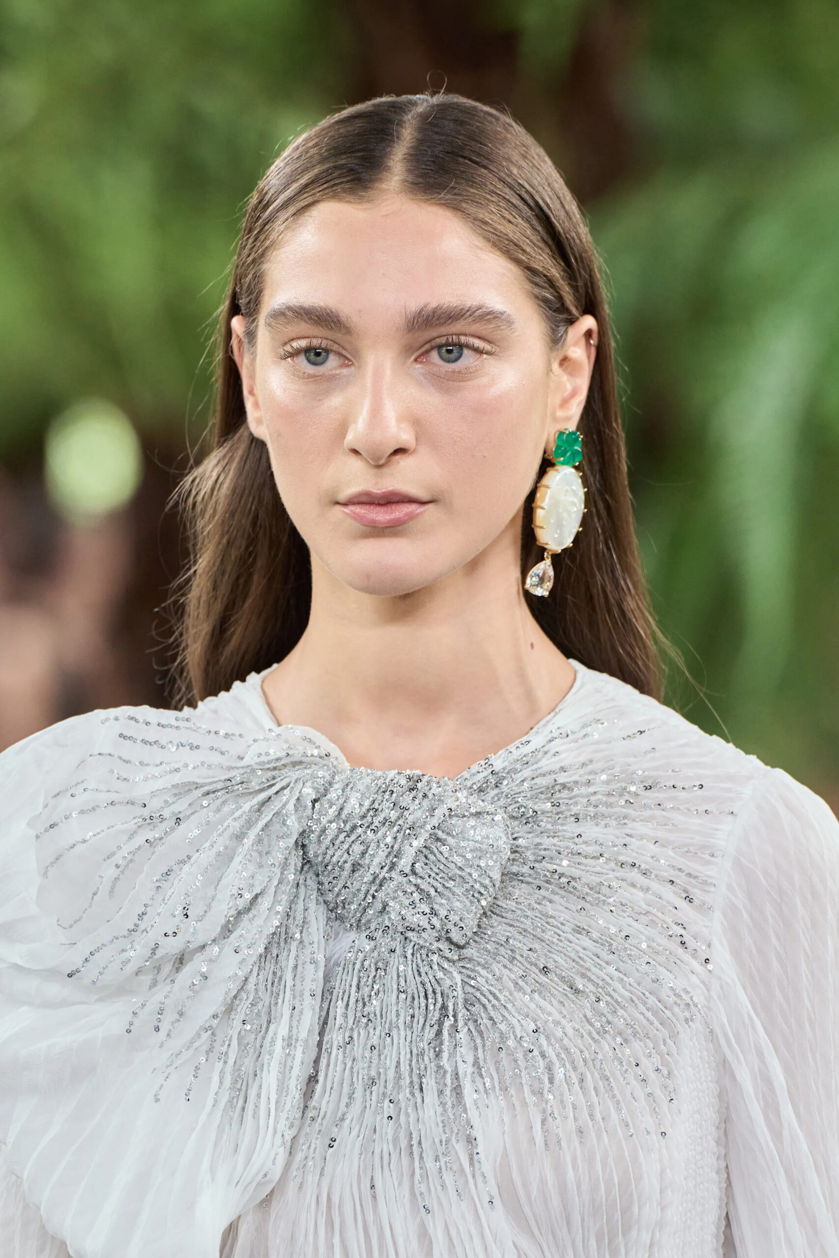Close-up portrait highlighting Dior Fall 2026 Couture shell earrings with emerald accents