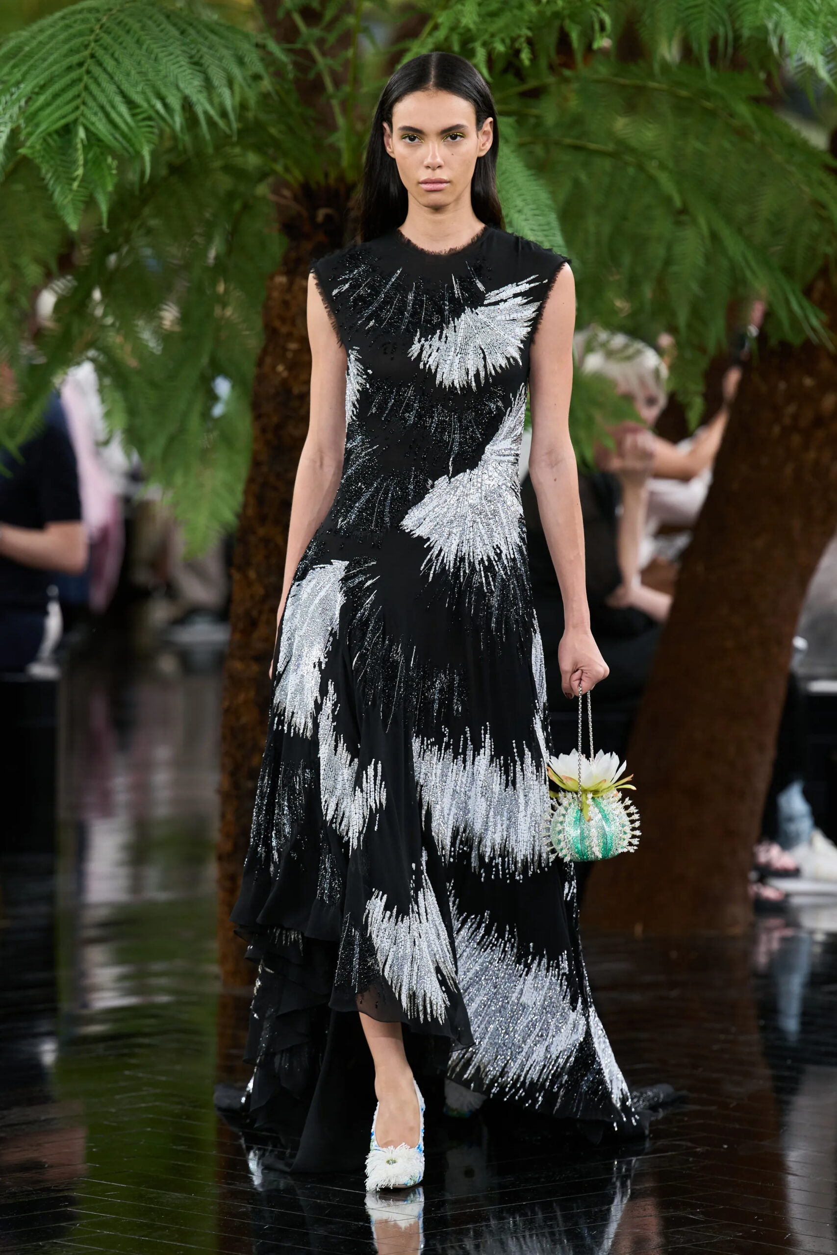 Model wearing a black embroidered Dior Fall 2026 Couture evening gown carrying a sculptural floral minaudière
