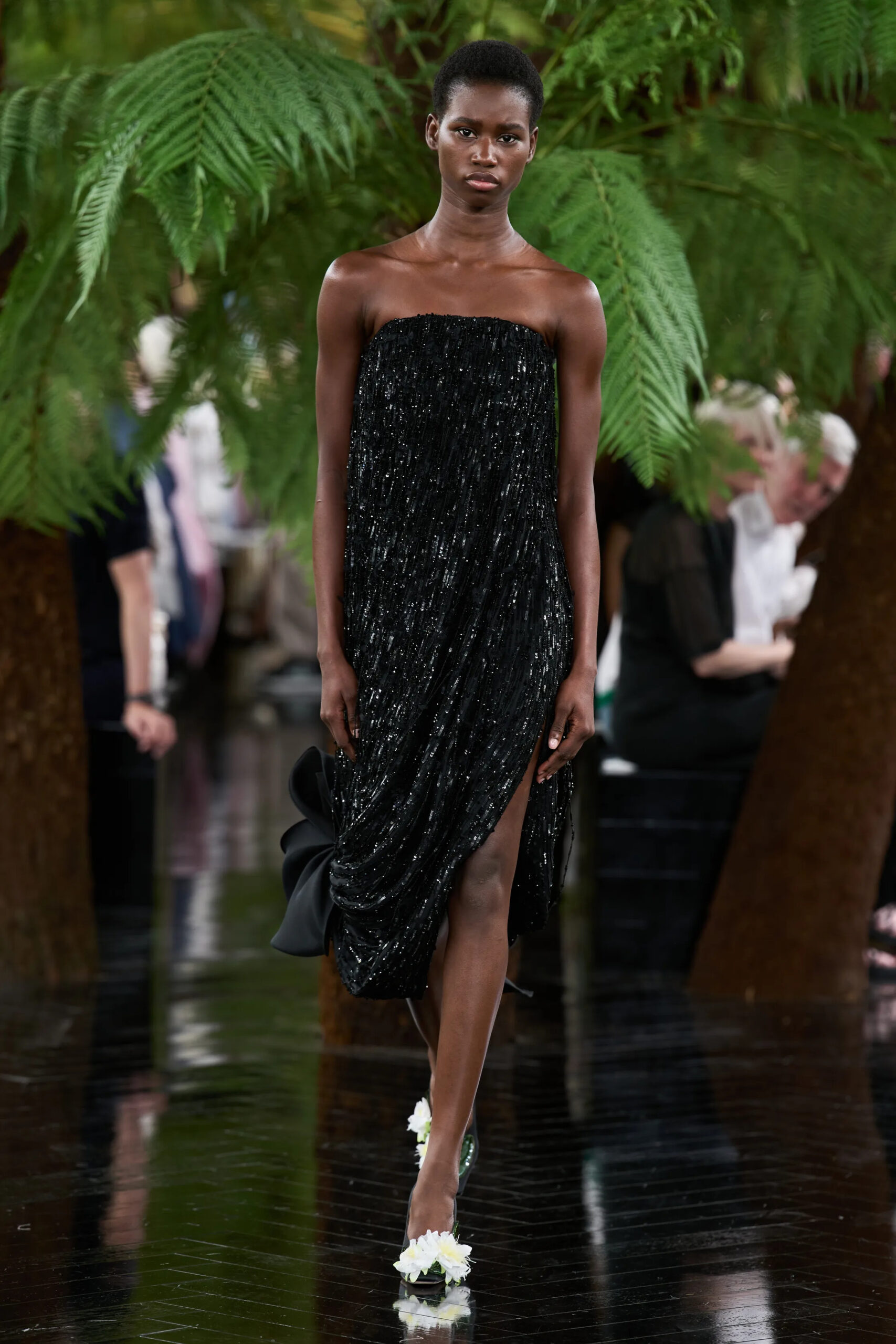 Model wearing a strapless black embellished Dior Fall 2026 Couture gown finished with floral pumps