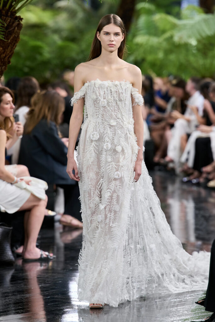 Model wearing the Dior Fall 2026 Couture bridal gown featuring hand embroidered floral textures, delicate botanical appliqué, and a sweeping train