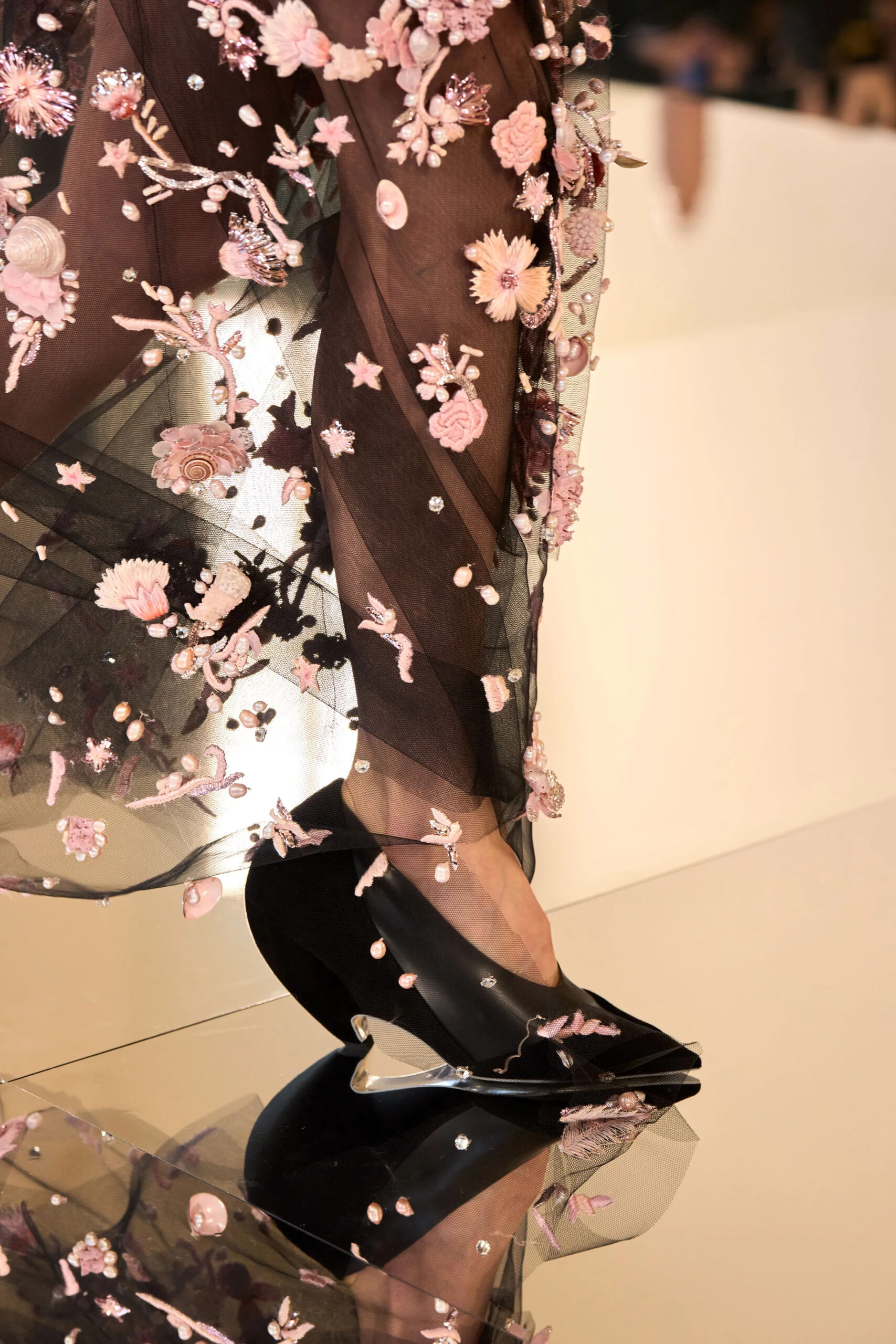 Close-up of black sheer Schiaparelli couture gown embroidered with pink florals and sculptural heel