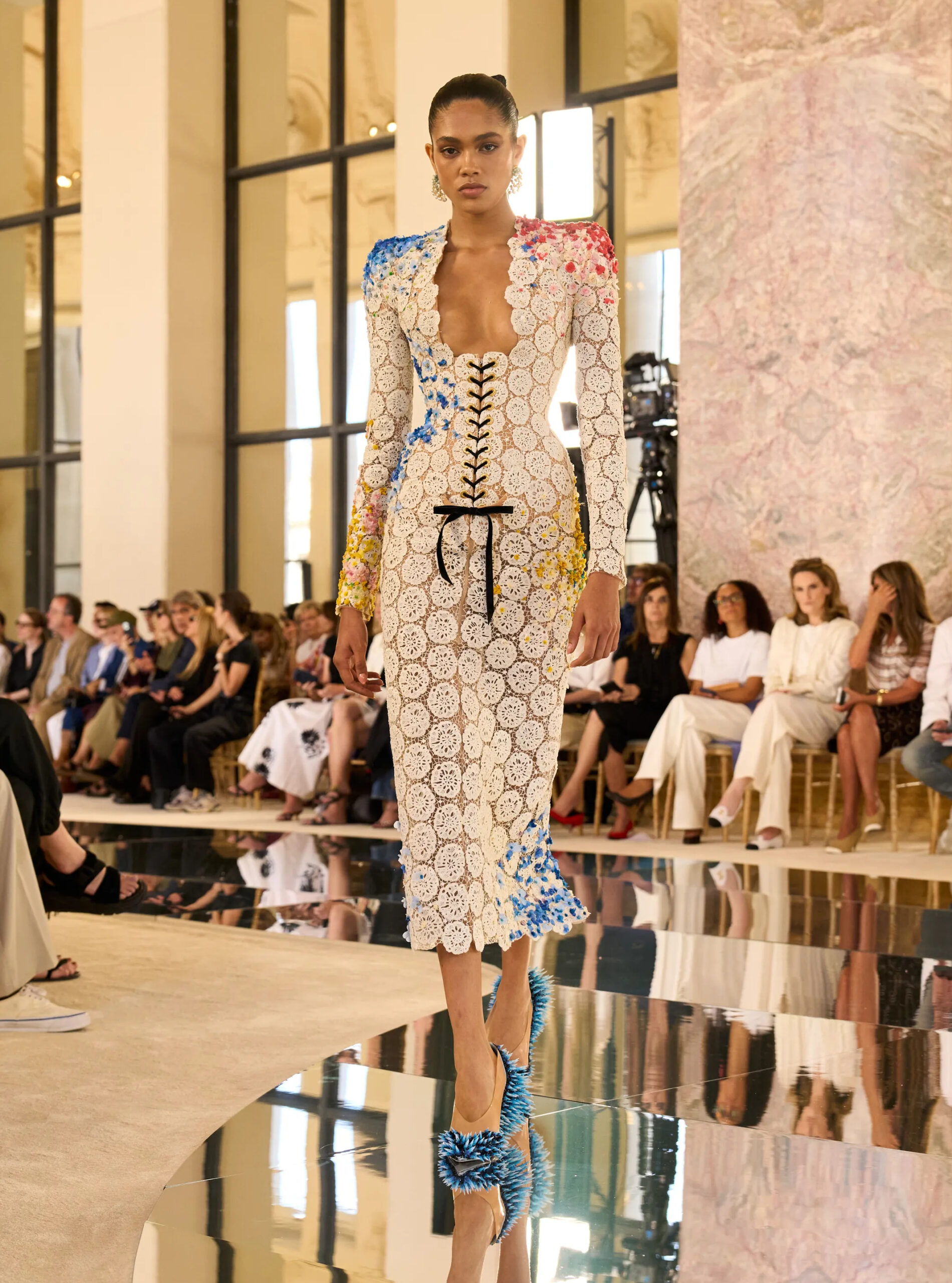White lace Schiaparelli couture dress embroidered with blue and yellow floral detailing.