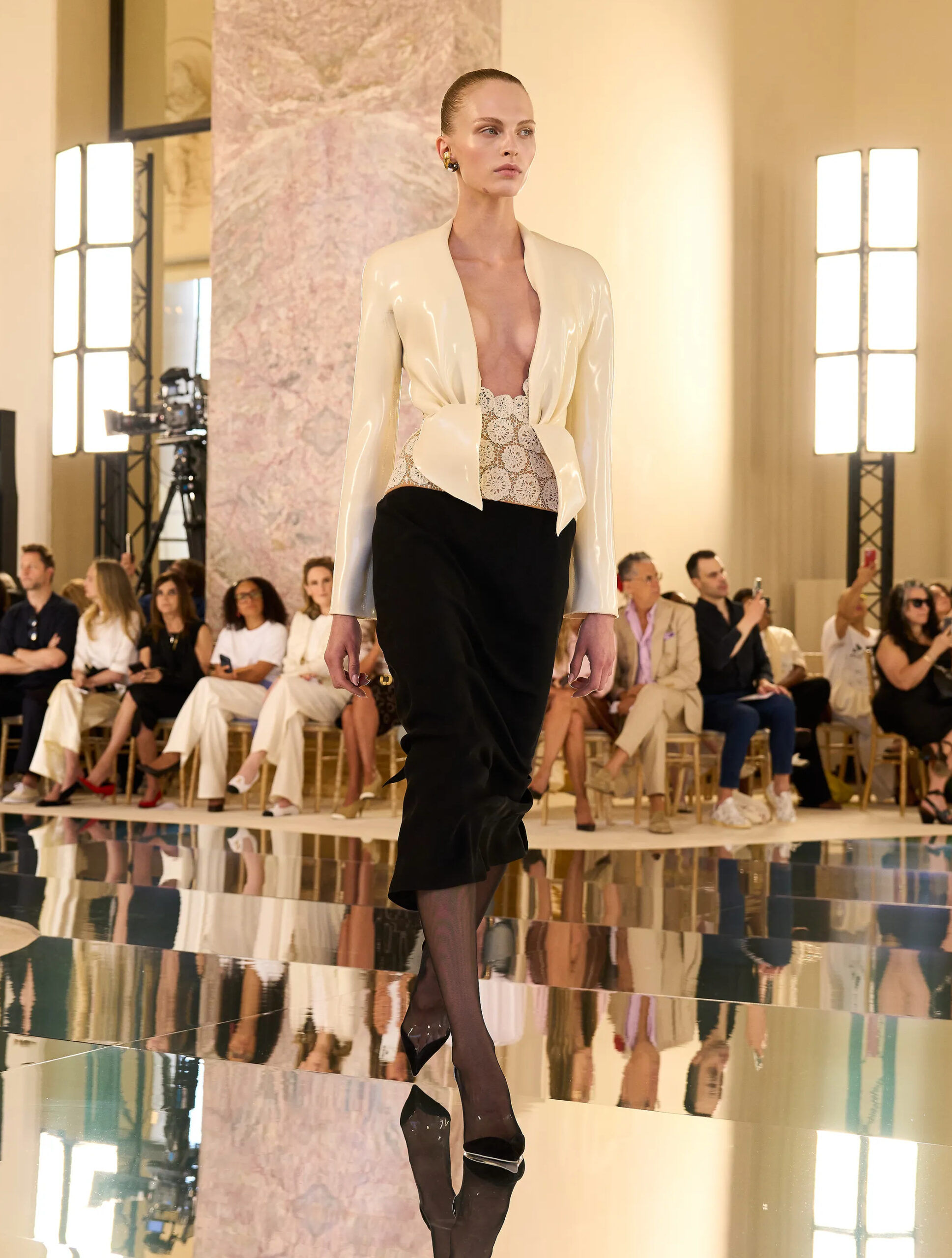 Model wearing an ivory sculptural Schiaparelli Fall Winter 2026 Couture jacket with plunging neckline over a dark draped skirt during Paris Haute Couture Week.